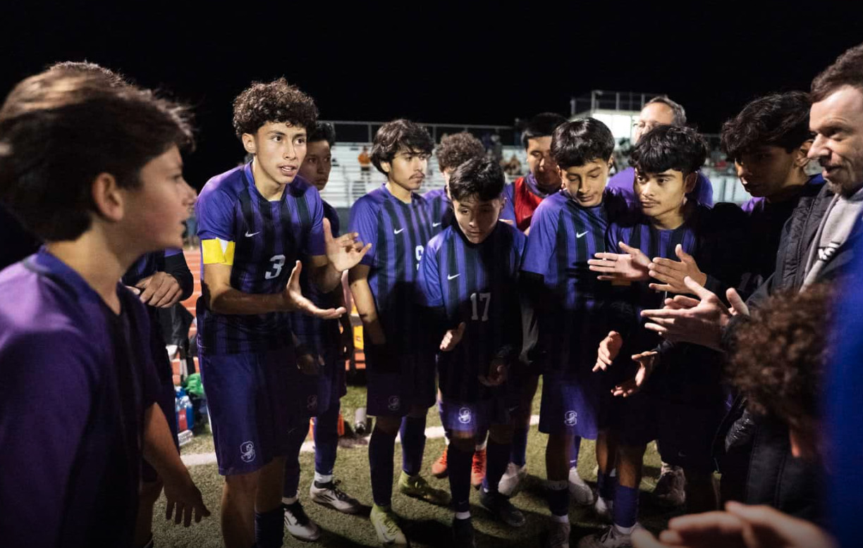 Sedona RRHS soccer players and coaches gathered in a team huddle. Open the full-size photo.